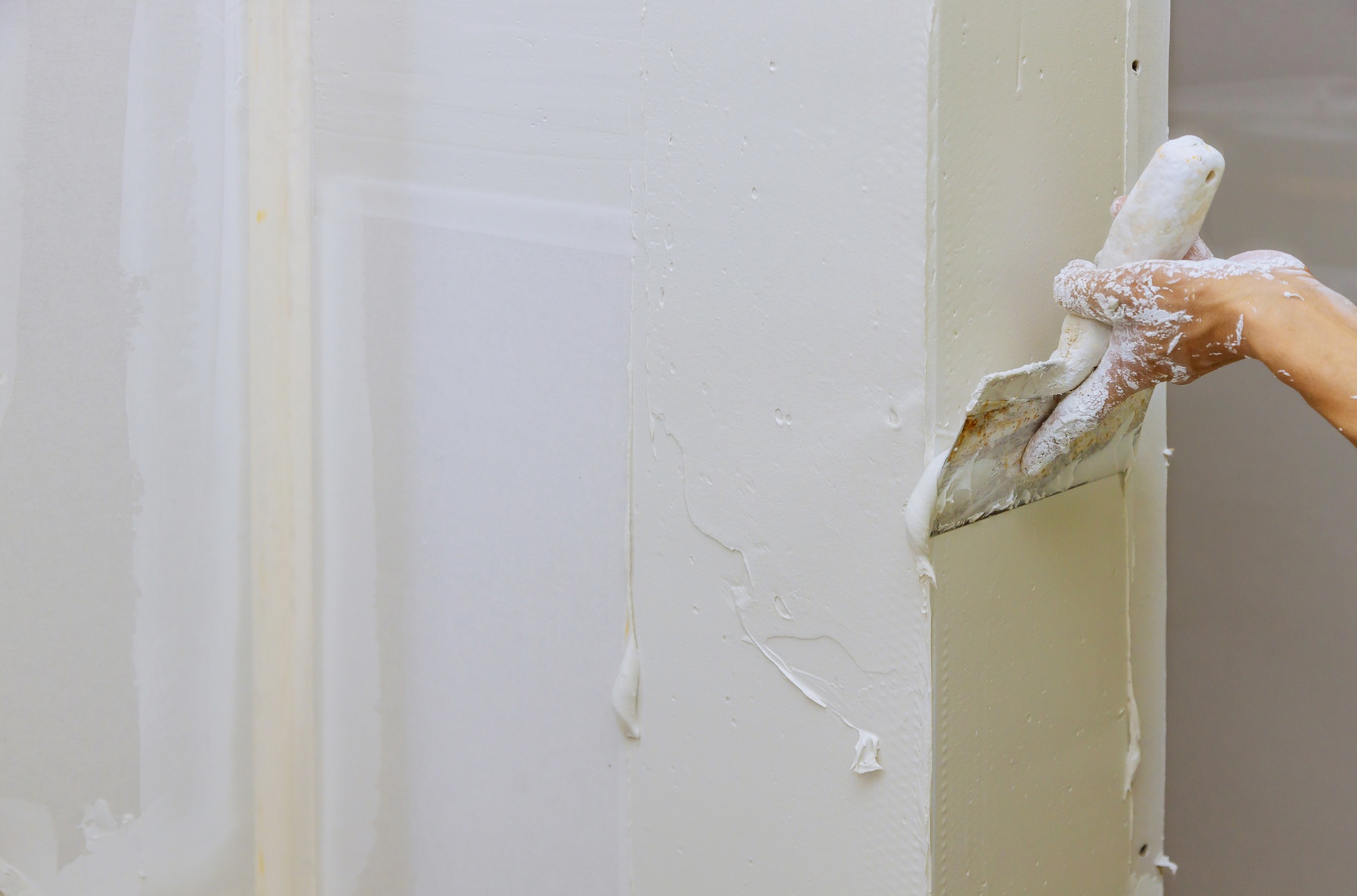 Hand of worker using gypsum plaster coating plaster walls construction